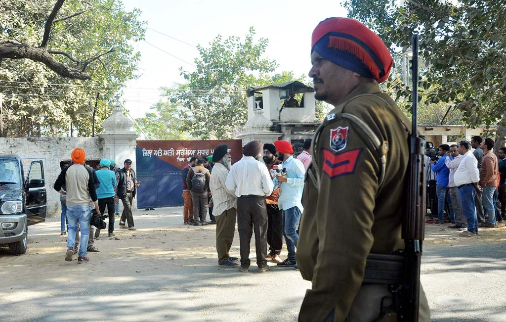 An Indian police personnel and onlookers stand near the gate of the Nabha maximum-security jail in Nabha in the state of Punjab on November 27, 2016. AFP / STR