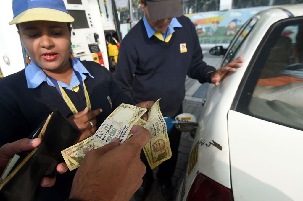 An Indian customer pays for fuel with old 500 rupee notes at a petrol station in New Delhi on December 2, 2016, the last day on which the old currency can be used to purchase fuel. AFP / Dominique Faget 