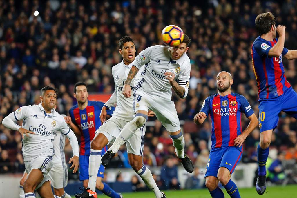 Real Madrid's defender Sergio Ramos (C) heads a ball to score the equalizer past Real Madrid's French defender Raphael Varane (3rdL) and Barcelona's Argentinian defender Javier Mascherano (R) during the Spanish league football match FC Barcelona vs Real M