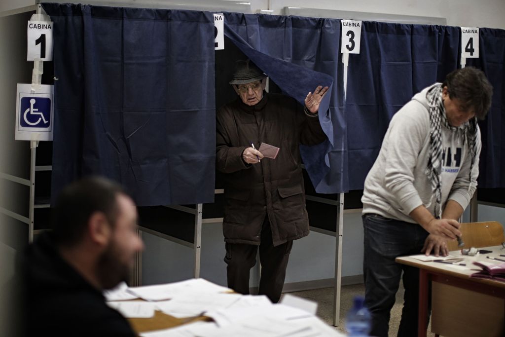 A man leaves a voting booth with his ballot during a referendum on constitutional reforms, on December 4, 2016 at a polling station in Milan.  AFP / MARCO BERTORELLO
