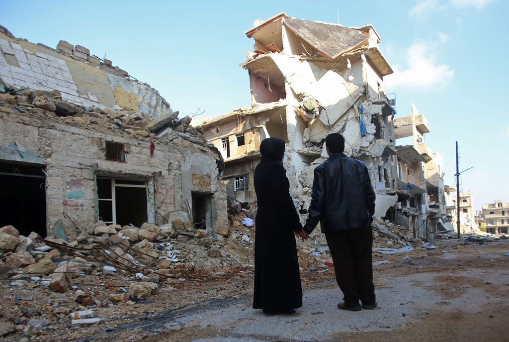 Kefa Jawish (L) and her husband Tajeddin Ahmed look a destroyed building in the Aleppo's northeastern Haydariya neighbourhood as they head to check their house for the first time in four years on December 4, 2016. 
AFP / Youssef KARWASHAN 