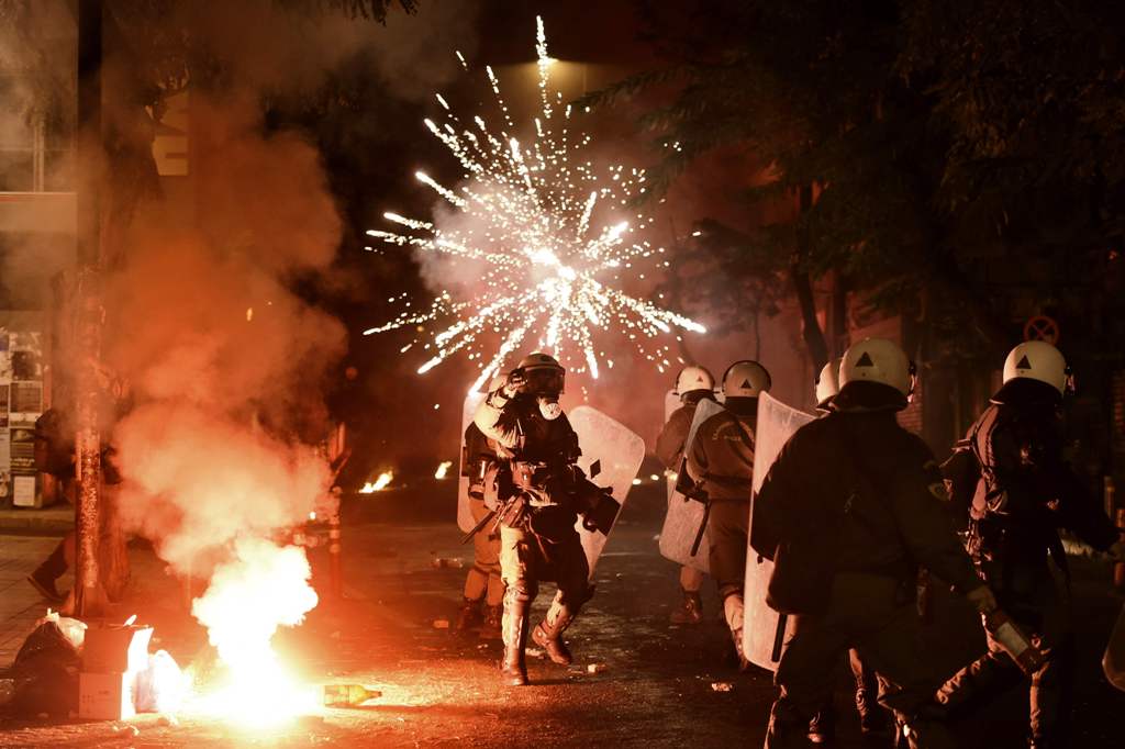 Police officers look on as a firework thrown by protesters explodes in front of them in the central district of Exarchia in Athens, on December 6, 2016, following a commemorative rally marking the eighth anniversary of the killing of teenager Alexandros G