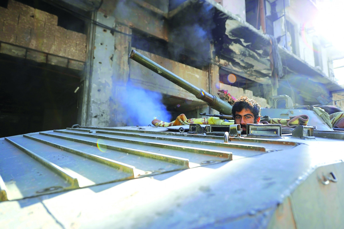 A member of Forces loyal to Syria's President Bashar Al Assad sits inside an armoured vehicle in a government held area of Aleppo, yesterday.