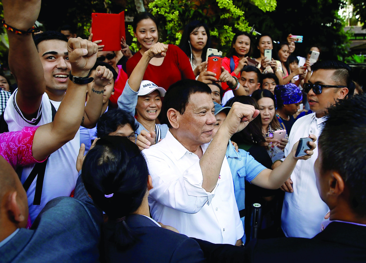 President Rodrigo Duterte poses for selfies with Filipinos after an orchid naming ceremony at Singapore Botanic Gardens, yesterday.