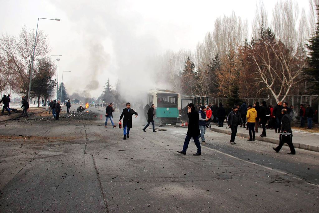 This picture obtained from the Ihlas News Agency shows a police officer and people walking next to the wreck of public bus following an explosion on December 17, 2016 in Kayseri, central Turkey. Turkey OUT / AFP / IHLAS NEWS AGENCY / IHLAS NEWS AGENCY