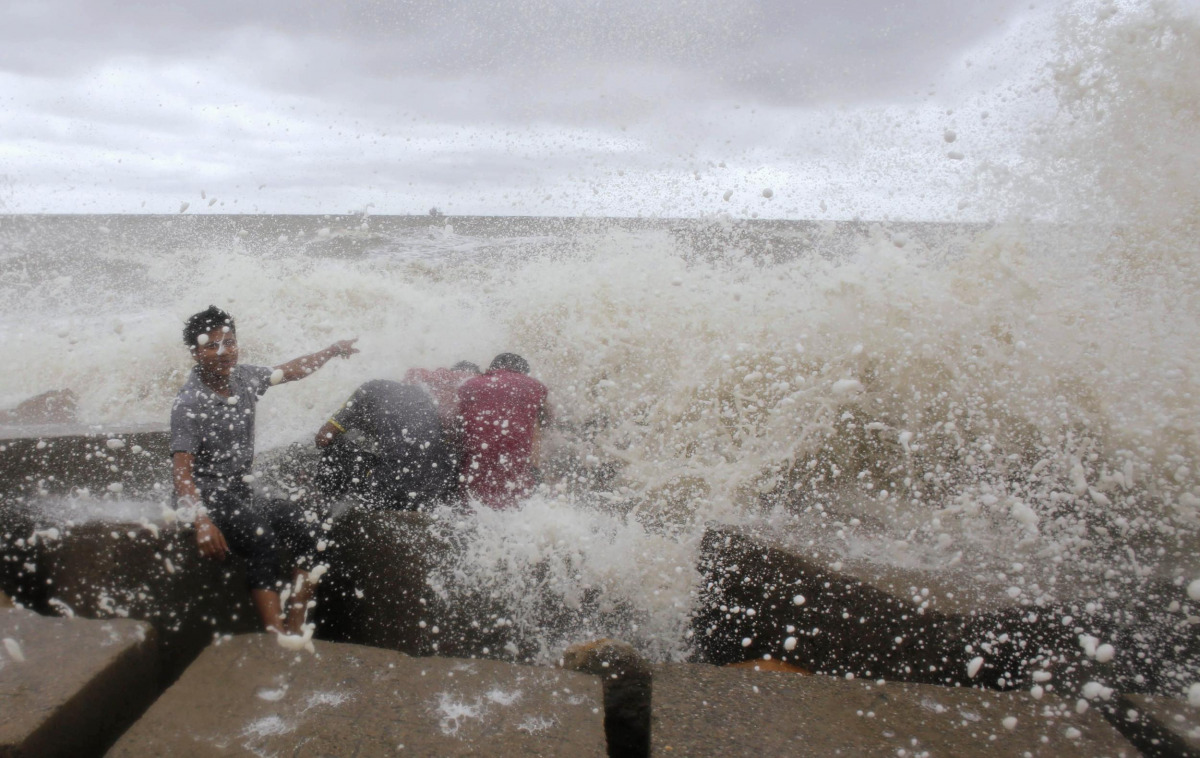 Waves crash into people sitting by the shore of the Bay of Bengal before cyclone Mahasen approaches in Chittagong May 16, 2013. REUTERS/Andrew Biraj