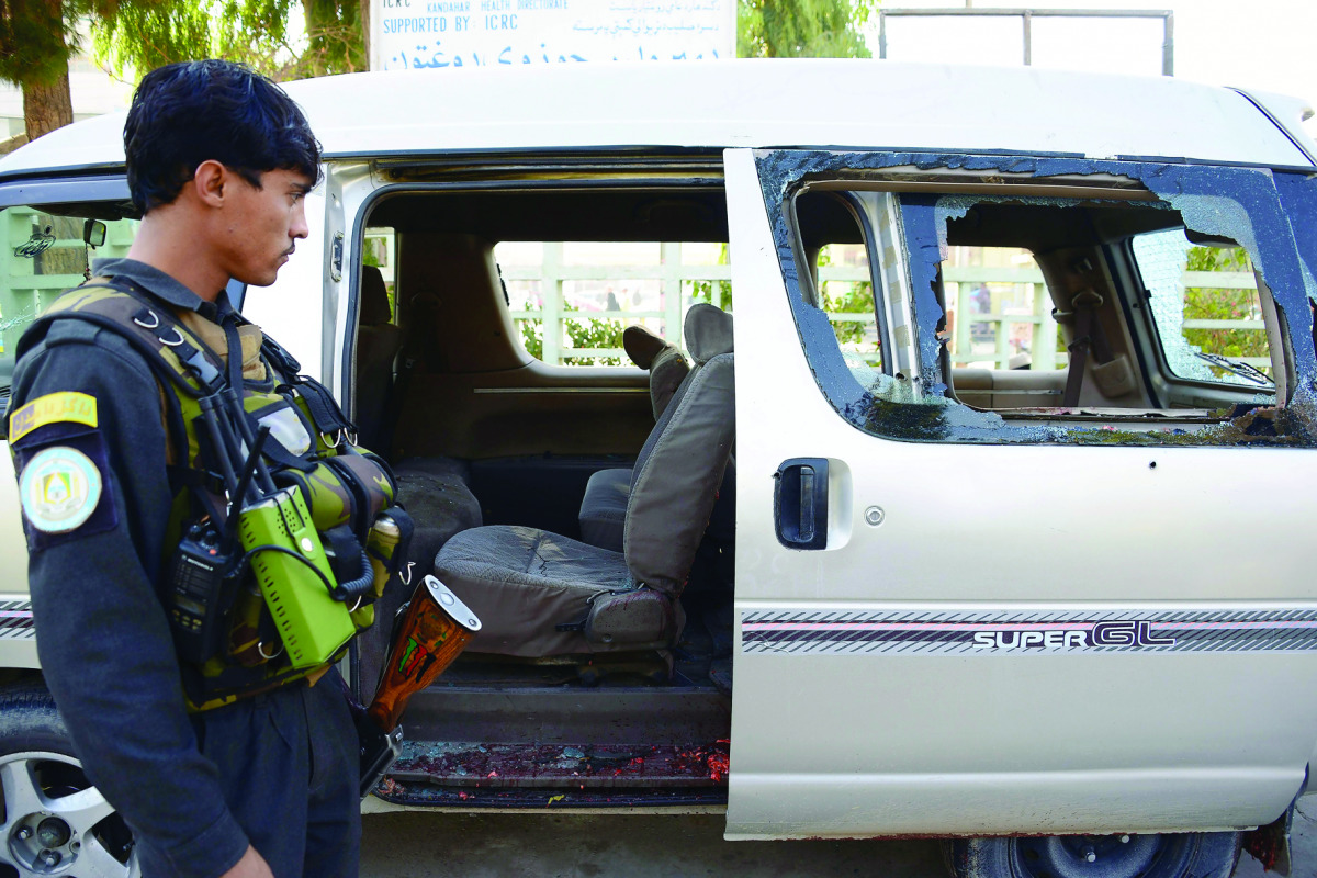 An Afghan policeman inspects a damaged vehicle in Kandahar, in which five female airport workers were killed, yesterday.