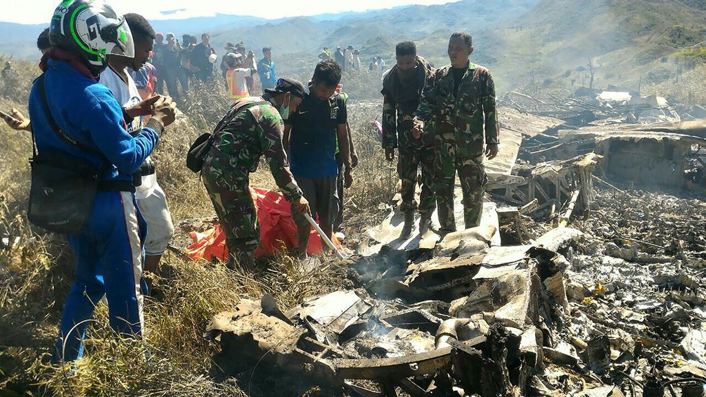 This handout picture released by search and rescue team and available on December 18, 2016 shows Indonesian soldiers examining the Hercules military plane A-1334 that crashed in Wamena on December 18, 2016. AFP / SEARCH AND RESCUE TEAM / HANDOUT