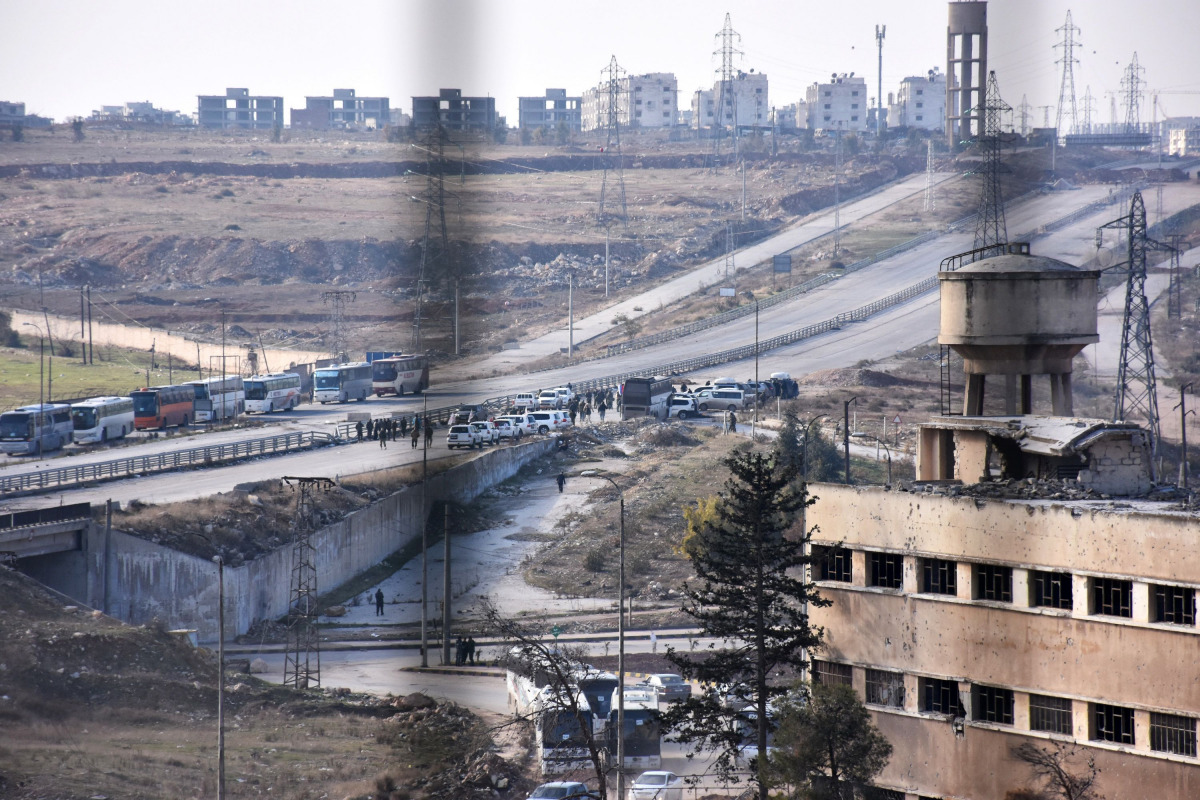 Vehicles from the International Red Cross and from the Syrian Red Crescent wait at the government-controlled crossing of Ramoussa, on the southern outskirts of Aleppo on December 18, 2016, during an evacuation operation of rebel fighters and civilians fro