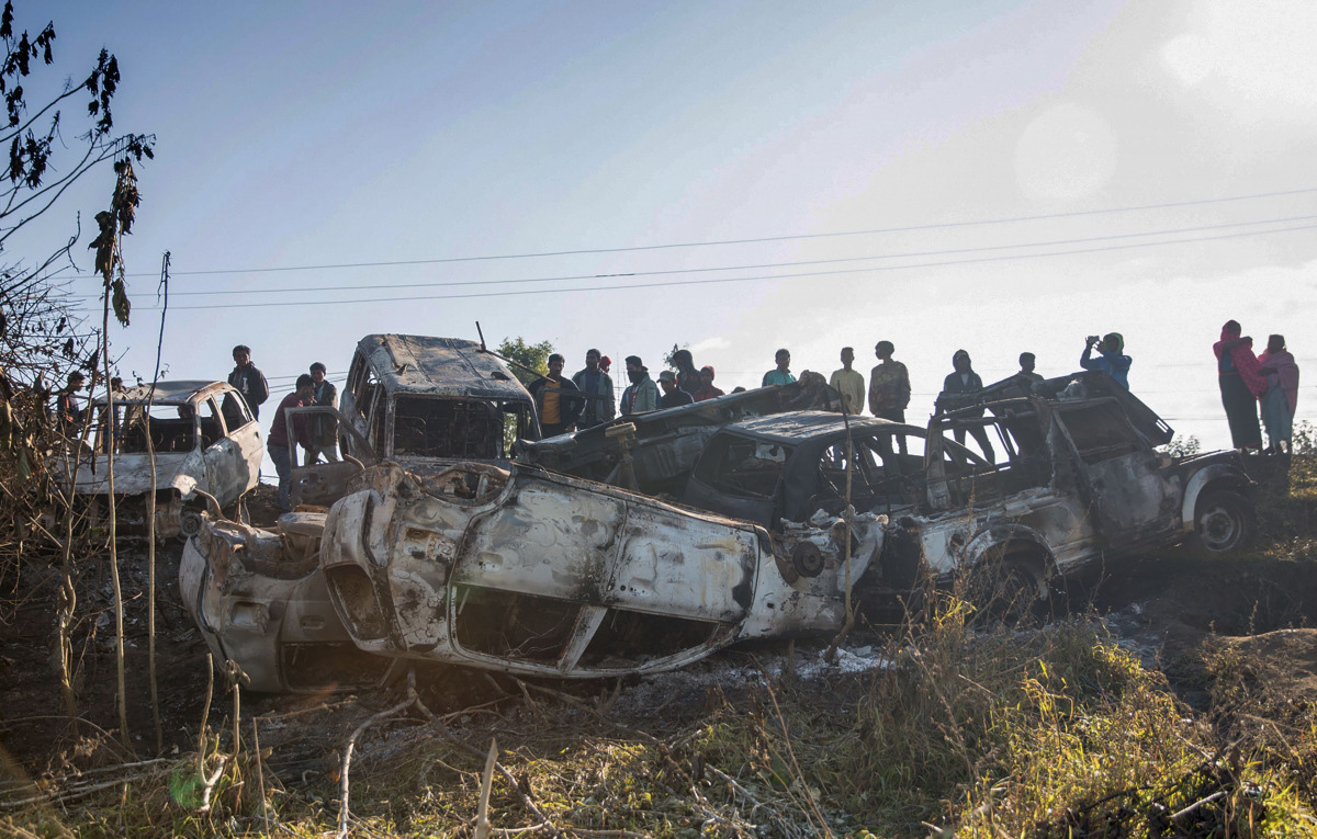 Bysanders gather to look at the burnt out shells of vehicles that had been set alight by protesters in Imphal, the capital of India's northeastern state of Manipur, on December 19, 2016. The violence began when protesters angry with an ongoing economic bl