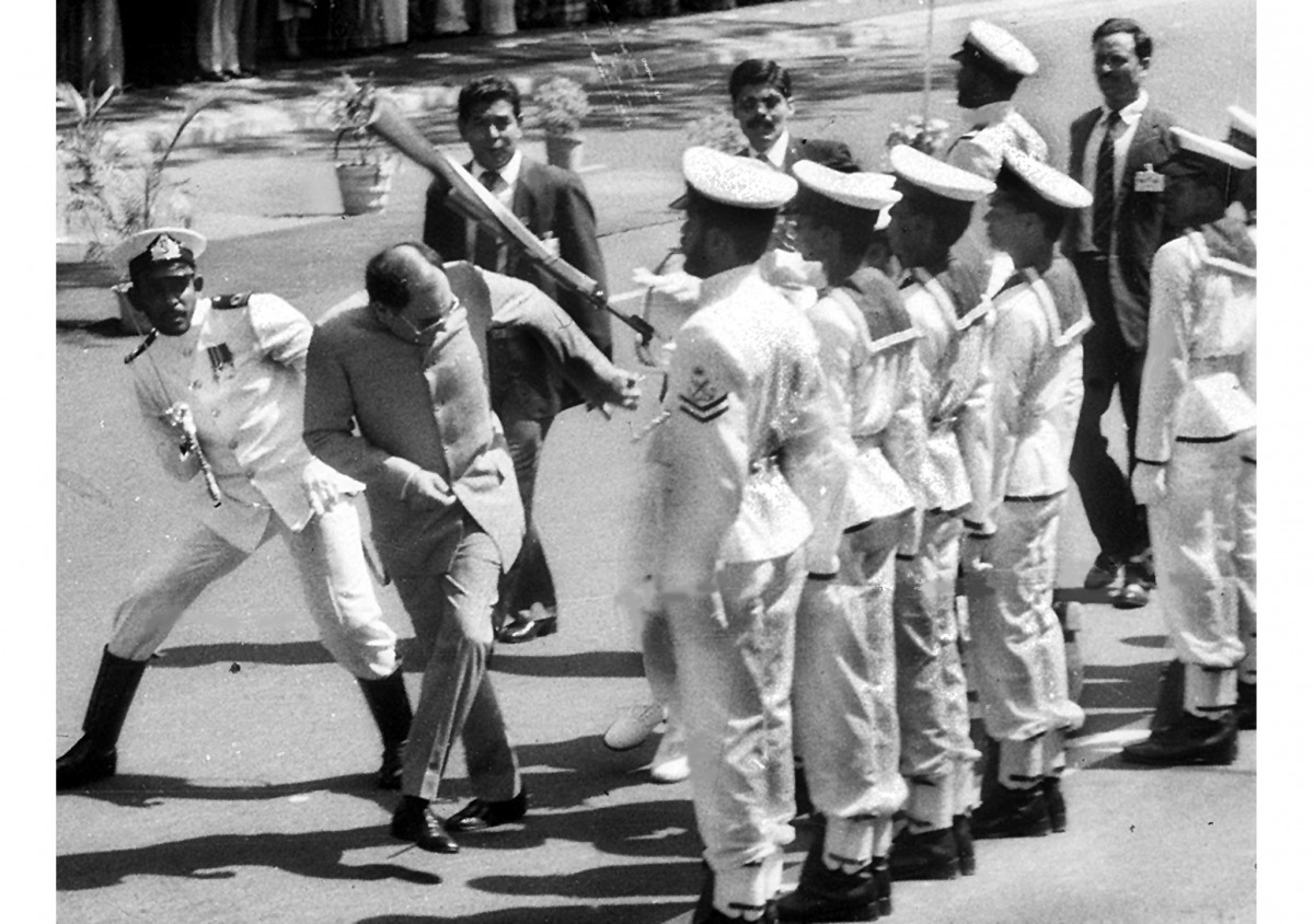 This file photograph taken on July 30, 1987, shows former Indian Prime Minister Rajiv Gandhi (C) ducking a rifle butt attack by a Sri Lankan naval rating during an honour guard in Colombo, after the visiting Indian leader signed a controversial peace pact