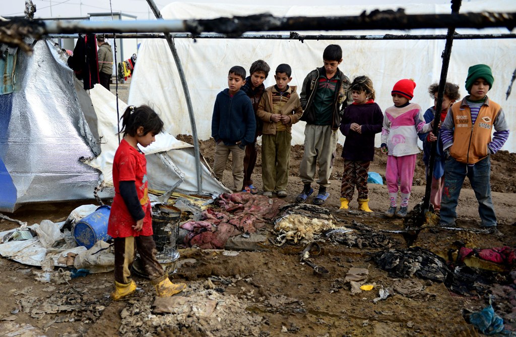 MOSUL, IRAQ - DECEMBER 21: Iraqi kids are seen around the burned tent after fire breaks out at the Khazir refugee camp where Internally relocated Iraqi people, in the Hasan Sam village near Mosul, Iraq on December 21, 2016. (Hamit Hüseyin - Anadolu Agency