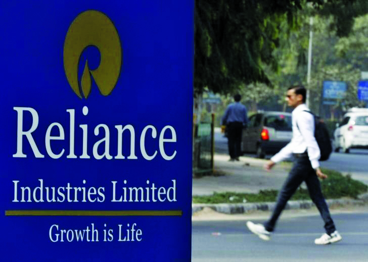 A man walks past a Reliance Industries Limited sign board installed on a road divider in Gandhinagar in Gujarat, India.