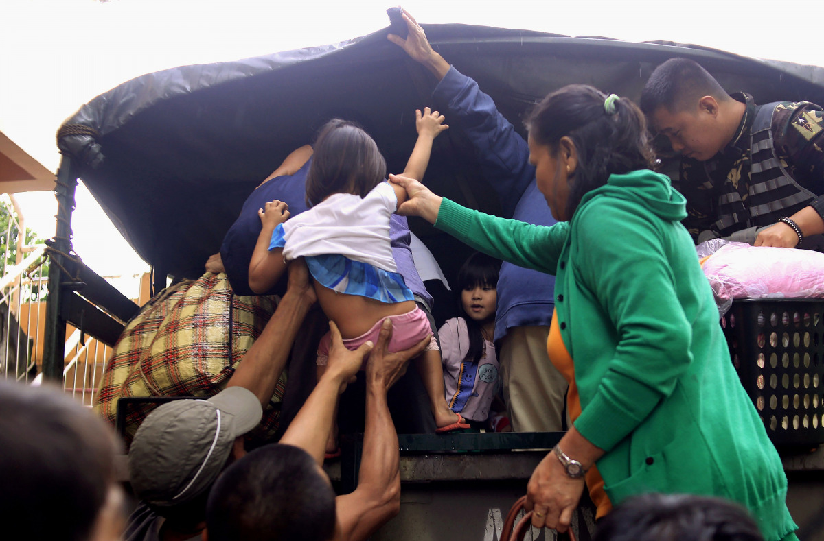 Residents are assisted into a truck after the local government implemented preemptive evacuations at Barangay Matnog, Daraga, Albay province on December 25, 2016, due to the approaching typhoon Nock-Ten. Babies, toddlers and old people were loaded onto mi