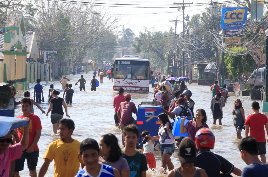 Residents wade across a flooded street brought by heavy rains and strong winds of Typhoon Nock-ten which cut through Naboa town, Camarines Sur, Bicol region, central Philippines December 27, 2016. REUTERS/Romeo Ranoco
