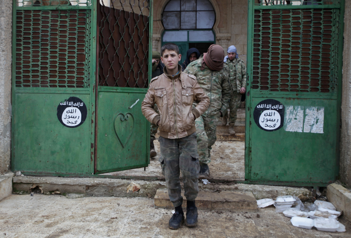 Rebel fighters walk out of a mosque in al-Rai town, northern Aleppo countryside, Syria December 30, 2016. On the gate are seen Islamic State logo stickers. REUTERS/Khalil Ashawi