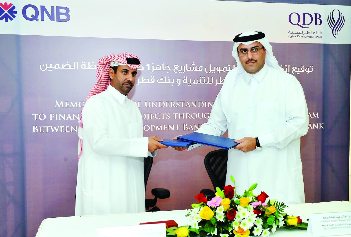 Khaled Al Nuaimi (left), AGM of SMEs at QNB, and Khalid Abdulla Al Mana, Executive Director of Business Finance at Qatar Development Bank (QDB), exchanging documents after the signing ceremony on Monday. Pic: Kammutty VP/The Peninsula