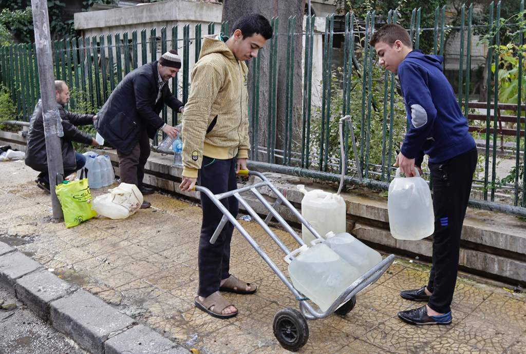 Syrians fill plastic containers with water at a public fountain in the capital Damascus on January 3, 2017. AFP / LOUAI BESHARA
