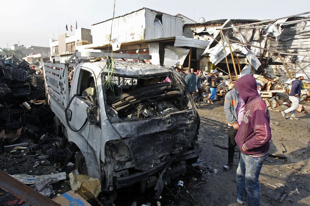 Iraqis inspect the site of an attack at Baghdad's main vegetable market on January 8, 2017. A suicide bomber blew up a car at the entrance of the market, killing at least 11 people and wounding dozens, security officials and medics said. / AFP / SABAH ARA