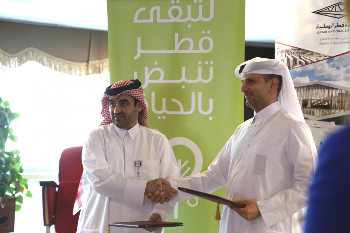 Engineer Abdul Aziz Ahmed Al Hammadi (left), Conservation and Energy Efficiency Department Manager at Kahramaa, and Engineer Saadi Al Said, Director for Administration and Planning at Qatar National Library, exchanging documents.