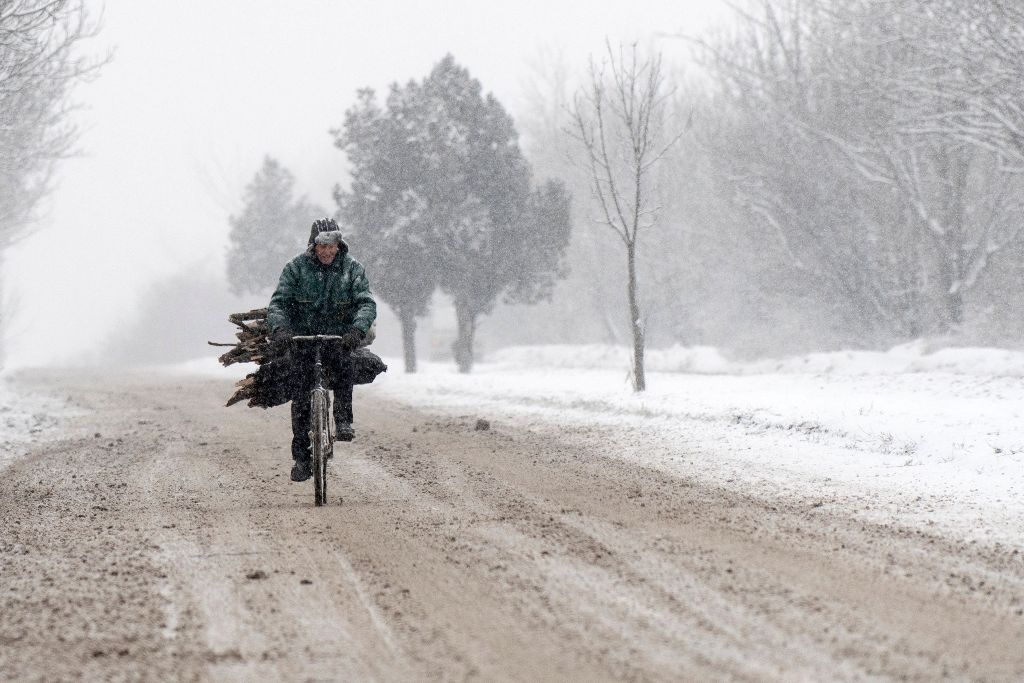 A man rides a bicycle laden with woods during a heavy snowfall in a suburb of Sofia, as temperatures dropped to minus 19 C in Bulgaria on January 10, 2017. / AFP / NIKOLAY DOYCHINOV