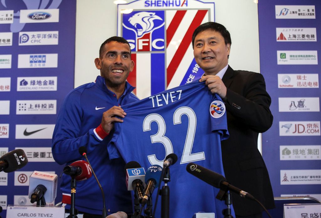 Argentine striker Carlos Tevez (L) poses with a jersey of his new club Shanghai Shenhua during a press conference in Shanghai on January 21, 2017. Tevez held his first press conference for his new club Shanghai Shenhua, which reportedly has made him the w