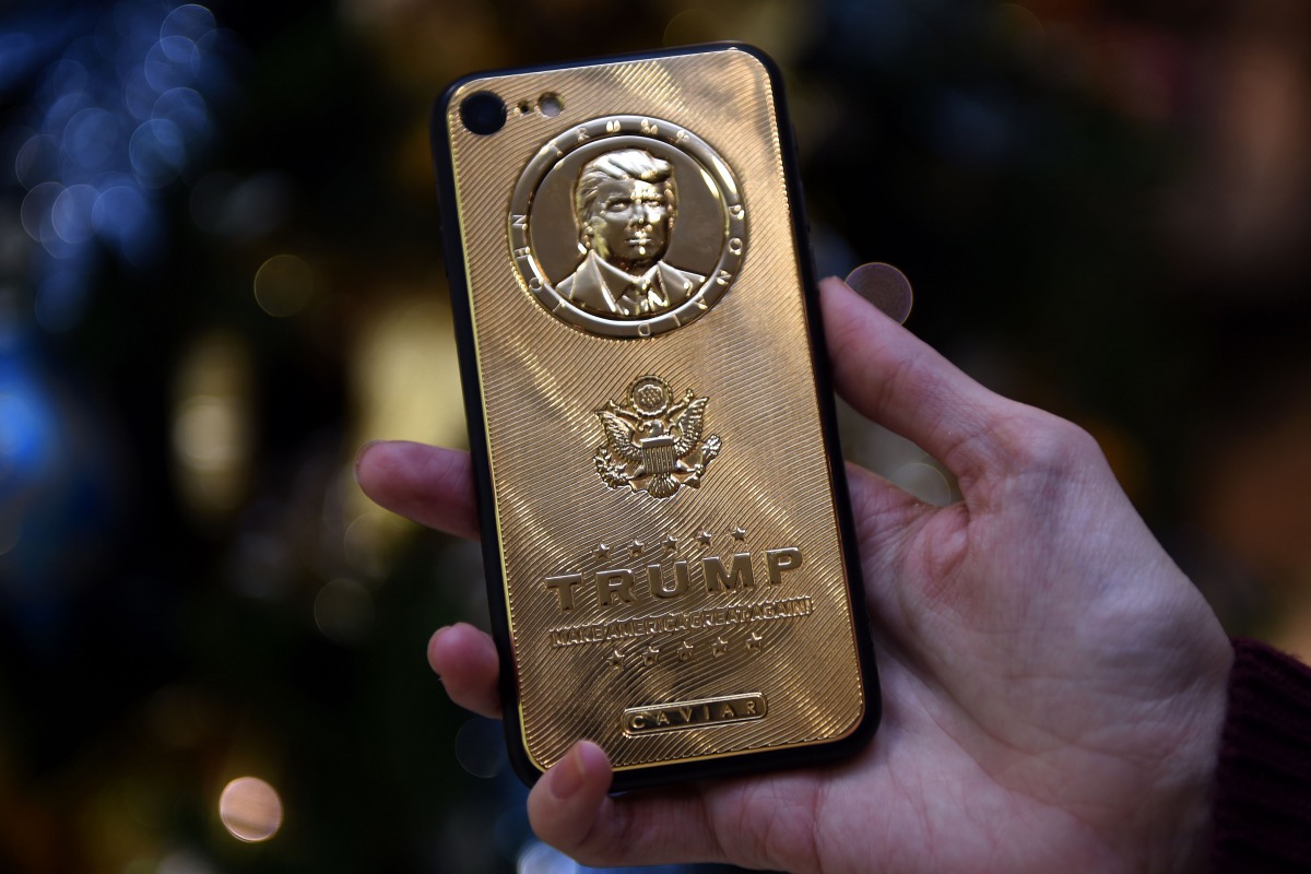 An employee of Caviar Phones, a Russian-Italian company specializing in smartphone customization displays a special gold-plated iPhone 7 smartphone bearing the likeness of  Trump (AFP) 