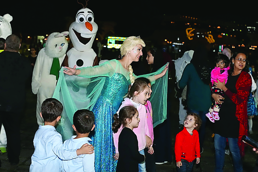 Children take photos with street performers at the fourth Katara Winter Festival.