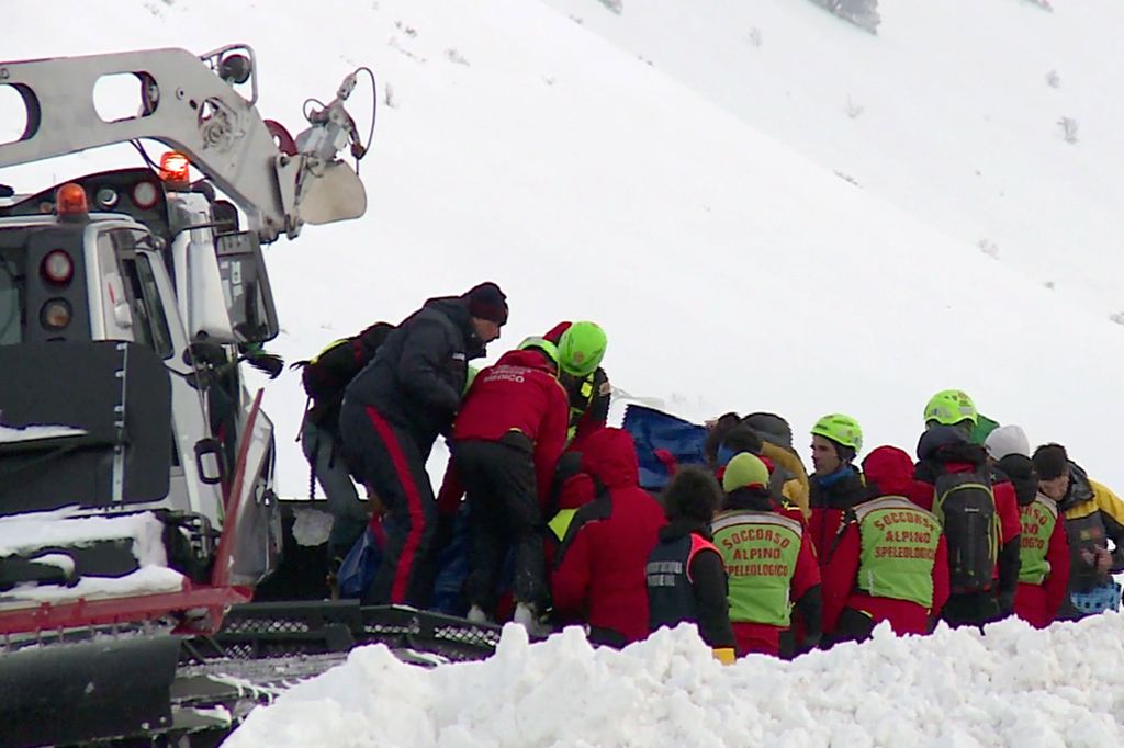 This video grab shows rescuers working to evacuate the bodies of six people killed in an helicopter crash, on January 24, 2017 in the mountains near the ski resort of Campo Felice, central Italy. The chopper came down near the ski resort of Campo Felice i
