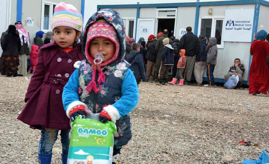 Displaced Iraqi children, who fled the violence around the northern Iraqi city of Mosul, receive aid at the al-Khazer refugee camp some 40 kilometres east of Arbil, on January 31, 2017. / AFP / Mahmud SALEH
