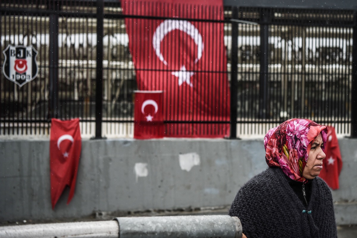 FILE PHOTO: A woman stands in front of Turkish national flags displayed at the site of the December 10 blasts outside Besiktas Vodafone Arena football stadium on December 13, 2016 in Istanbul (AFP / OZAN KOSE) 