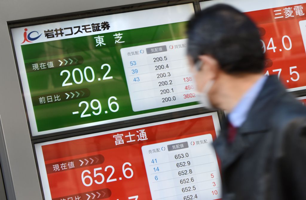 A businessman looks at an electric quotation board flashing the share price of Japan's Toshiba (top/L) in front of a securities company in Tokyo on February 15, 2017.  AFP / TORU YAMANAKA
