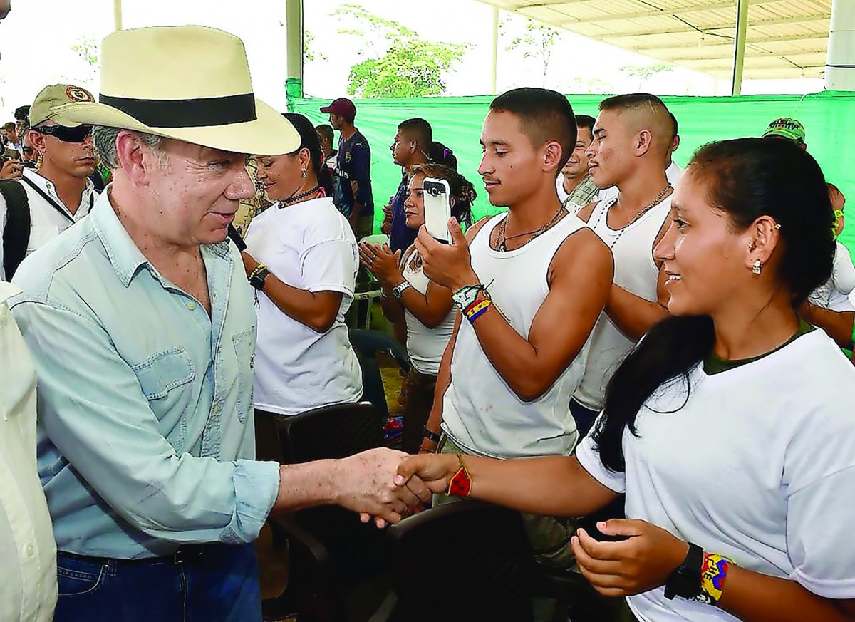 Colombian President Juan Manuel Santos (left) shaking hands with a FARC-EP leftist guerrilla during his visit to a Transitional Standardization Zone in La Carmelita, Puerto Asis municipality, yesterday.