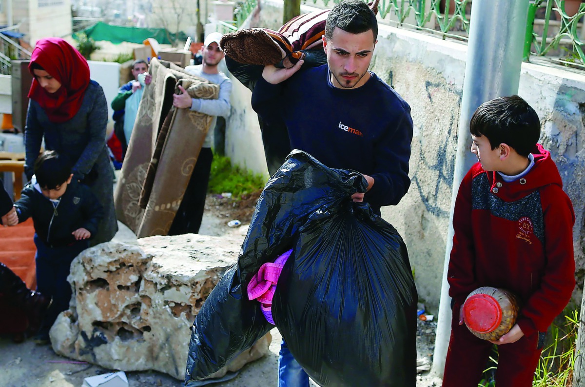 A Palestinian man gathers his belongings outside his house that was demolished by Israeli army bulldozers in the Arab East Jerusalem, yesterday.