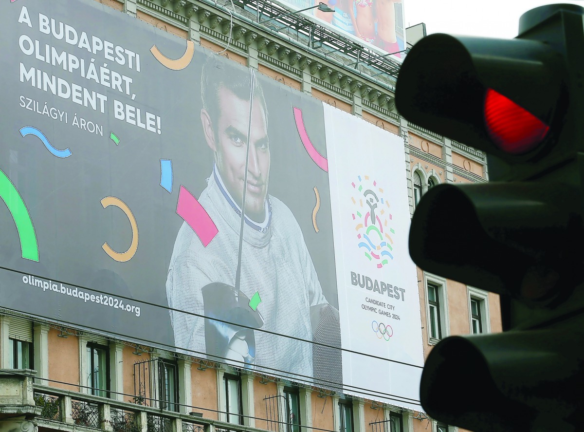 Traffic lights switch to red in front of a Hungarian pro-Olympics billboard with two-times sabre fencing Olympic champion Aron Szilagyi advertising the Games, billboard saying 