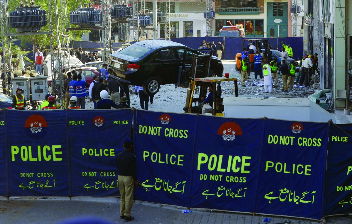 Pakistani security officials examine the site after a bomb attack in Lahore, yesterday.