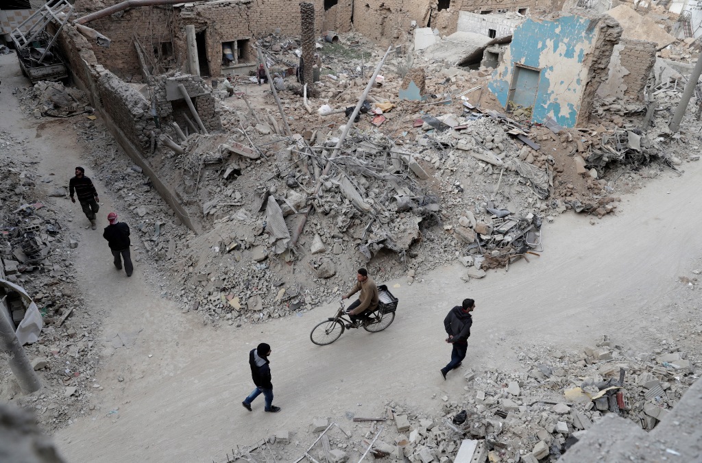 Syrians walk past the rubble of destroyed buildings in the rebel-held town of Douma, on the eastern outskirts of the capital Damascus, on February 27, 2017.  AFP / Abd Doumany