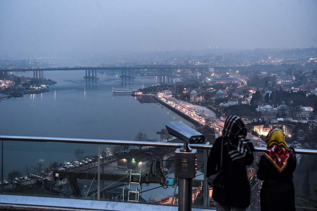Women stand at a scenic view point overlooking the Golden Horn in Istanbul on February 27, 2017. / AFP / OZAN KOSE