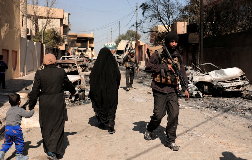 A special forces member walks past displaced Iraqis as they flee their homes in Al Mansour district, while Iraqi forces battle with Islamic State militants, in western Mosul, Iraq March 6, 2017. REUTERS/Zohra Bensemra
