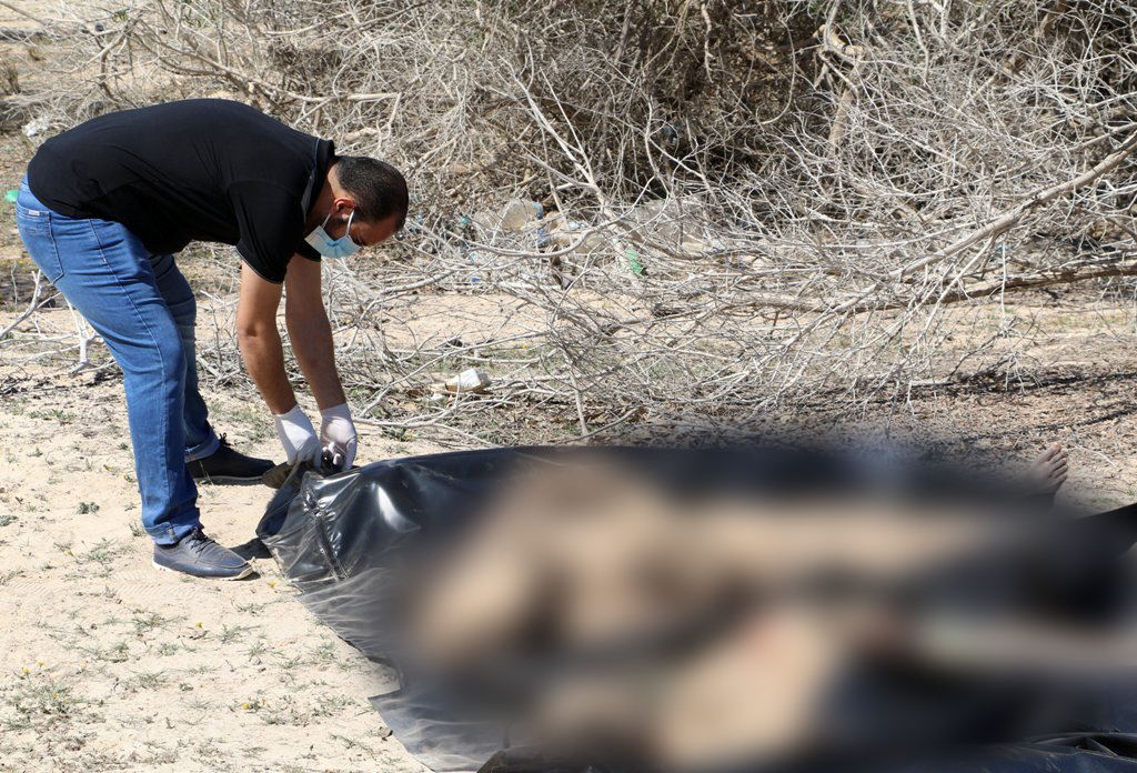 A rescue worker removes dead bodies of migrants, that were buried by people on the beach, after they were recovered by the Libyan Red Cross to be re-buried in a cemetery designated for migrants, in the western coastal city of Sabratha, Libya, March 7, 201