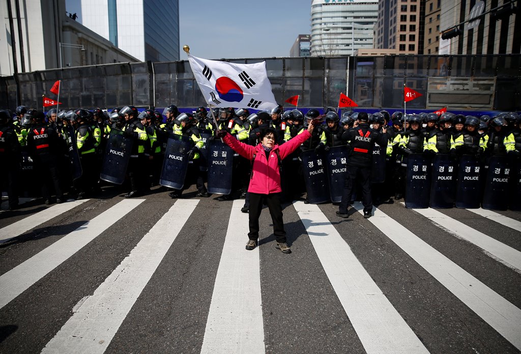 A woman supporting South Korea's ousted leader Park Geun-hye holds the national flag in front of police before the start of a rally supporting Park in Seoul, South Korea, March 11, 2017.REUTERS/Kim Kyung-Hoon 