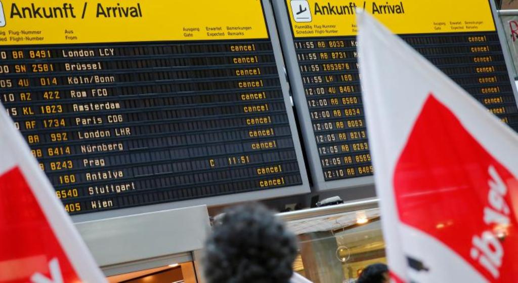 Members of Germany's Verdi union protest with flags in front of a display with canceled flights during a warning strike by ground services, security inspection and check-in staff at Tegel airport in Berlin, Germany March 10, 2017. REUTERS/Hannibal Hanschk