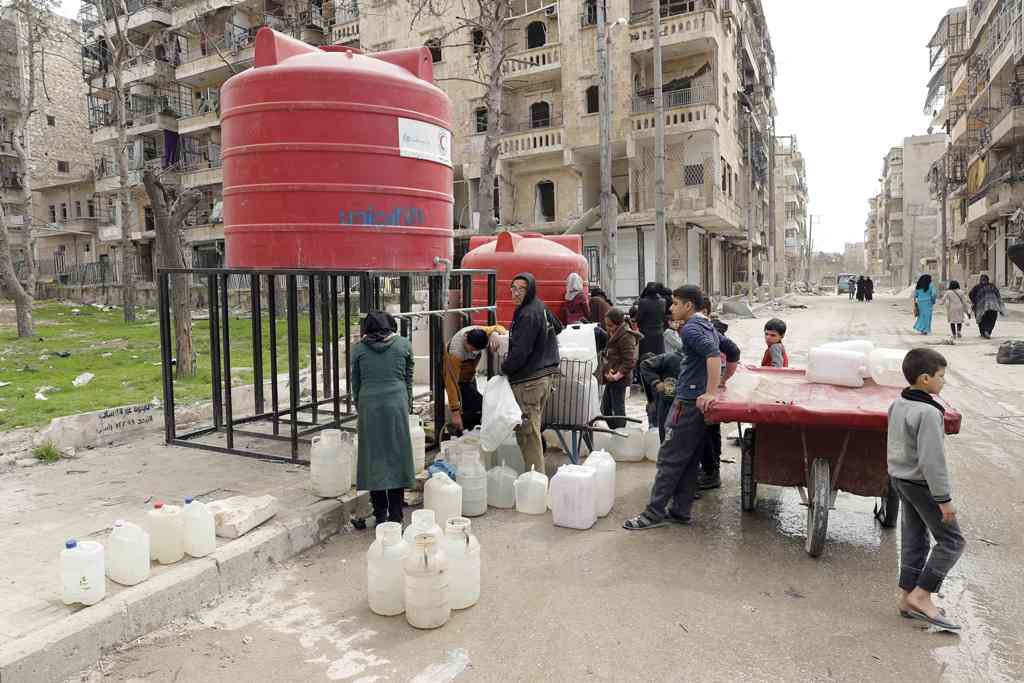 Syrians stand in queue next to a water reservoir in the once rebel-held Shaar neighbourhood in the Northern Syrian city of Aleppo on March 9, 2017. / AFP / JOSEPH EID
