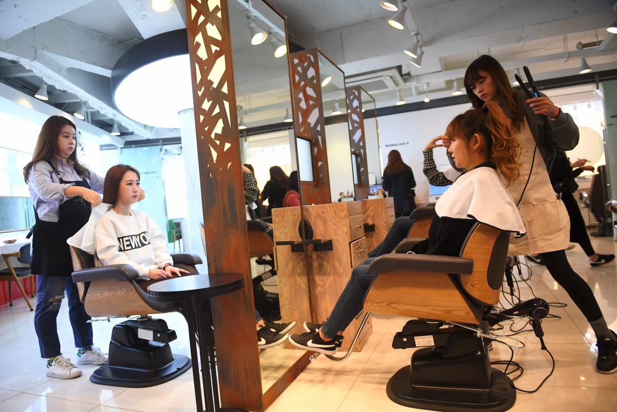 This picture taken on March 16, 2017 shows Jung Hye-Yoon (R) and Lee So-Young (L), members of K-pop group SixBomb, having their hair done at a beauty parlour in Seoul.  AFP / Jung Yeon-Je