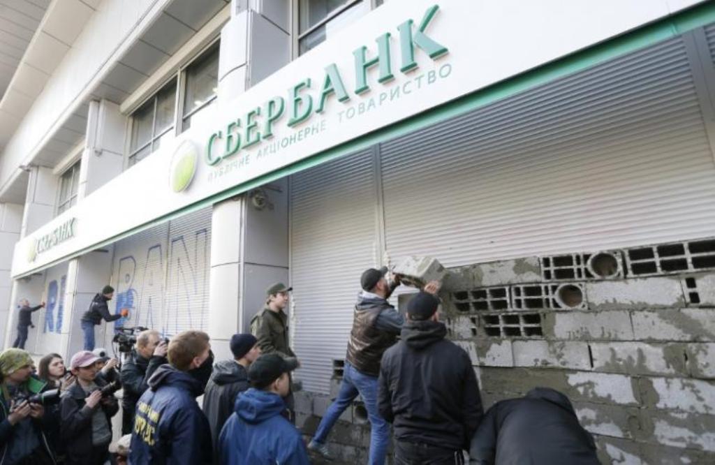 Members and supporters of the National corp political party erect a wall of concrete blocks and paint graffiti outside a branch of Sberbank, which is the local subsidiary of Russia's largest lender, during a protest in Kiev, Ukraine, March 13, 2017. REUTE
