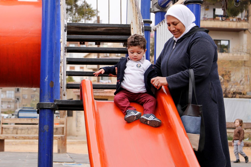 Hajar Saleh helps her grandson Jaafar playing on a slide inside a garden in the Damascus district of Mezzeh, Syria March 30, 2017. Picture taken March 30, 2017. REUTERS/Omar Sanadiki
