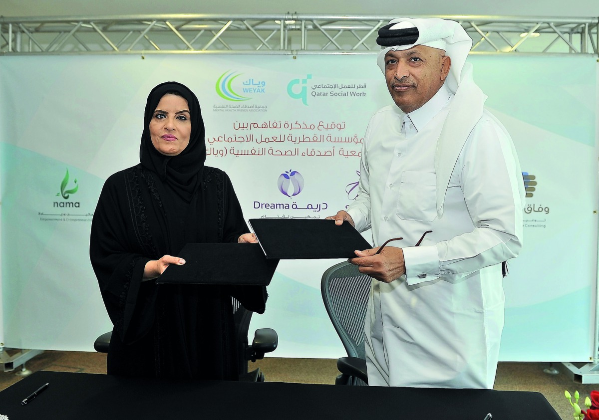 Amal bint Abdullatif Al Mannai (left), CEO of Qatar Foundation for Social Work; and  Hassan bin Abdullah Al Ghanim, Deputy Chairman of Mental Health Friends Association Weyak; exchange documents after signing an MoU at Tornado Tower recently.  Pic: Baher 