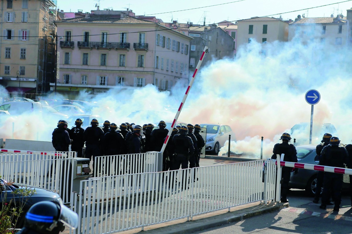Policemen stand in front of smoke during a clash with protesters after a meeting of the French far-right Front National (FN) party candidate for the presidential election in Ajaccio, on the French Mediterranean island of Corsica, yesterday.