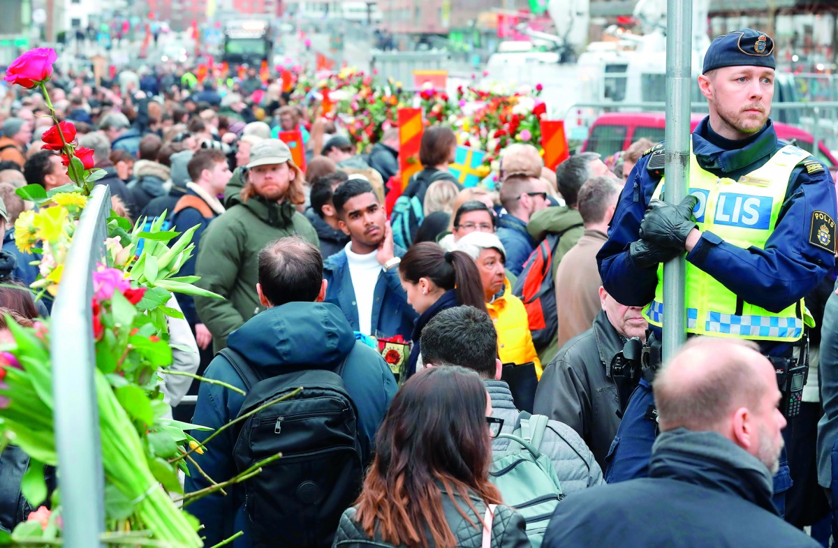 People gather at a makeshift memorial near the scene Ahlens in Stockholm, , yesterday.