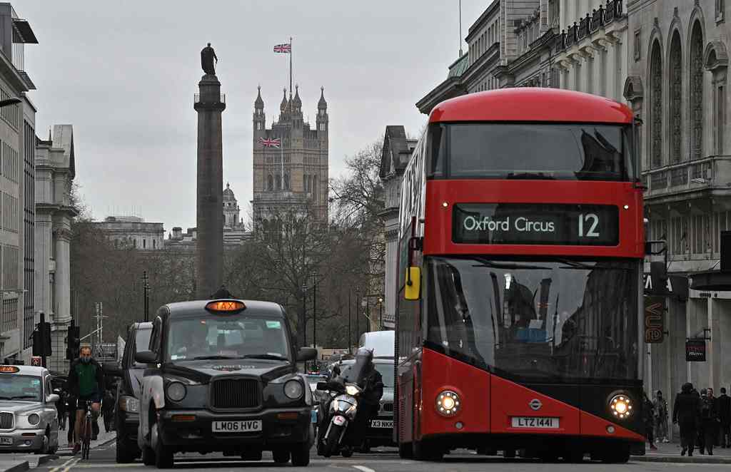 (FILES) This file photo taken on March 20, 2017 shows Union flags flying above and in front of Britain's Houses of Parliament as a black London taxi cab and red London bus wait at traffic lights in central London on March 20, 2017. AFP / Justin Tallis 